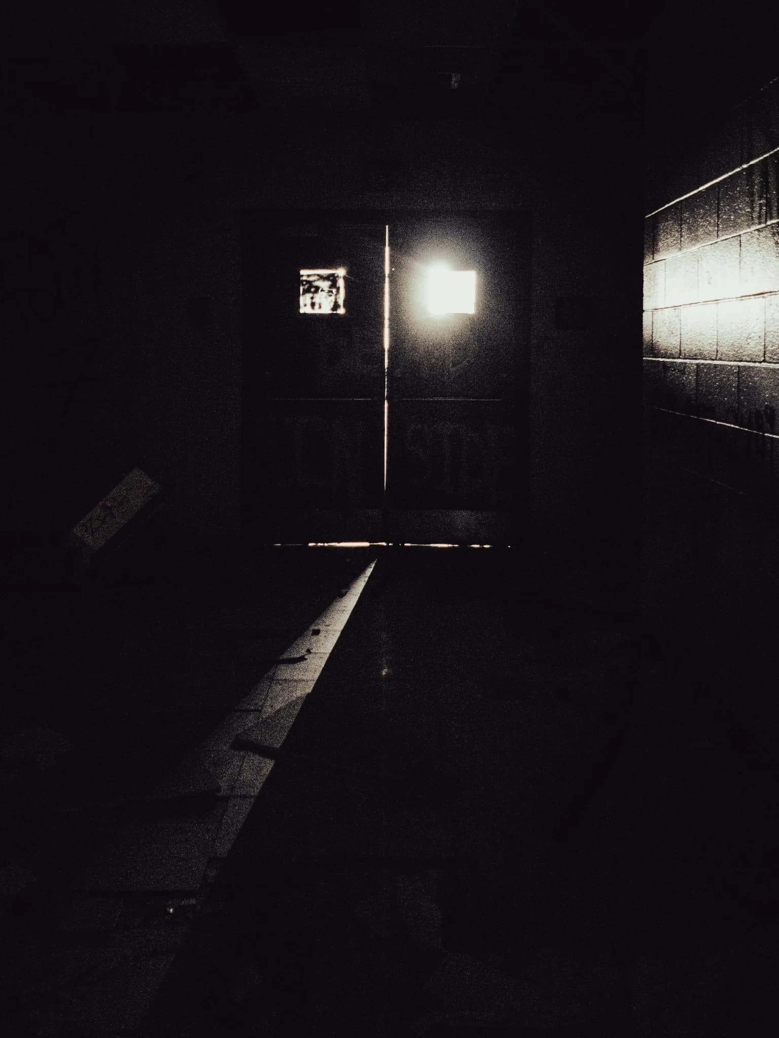 A narrow beam of light entering a nearly black abandoned hallway